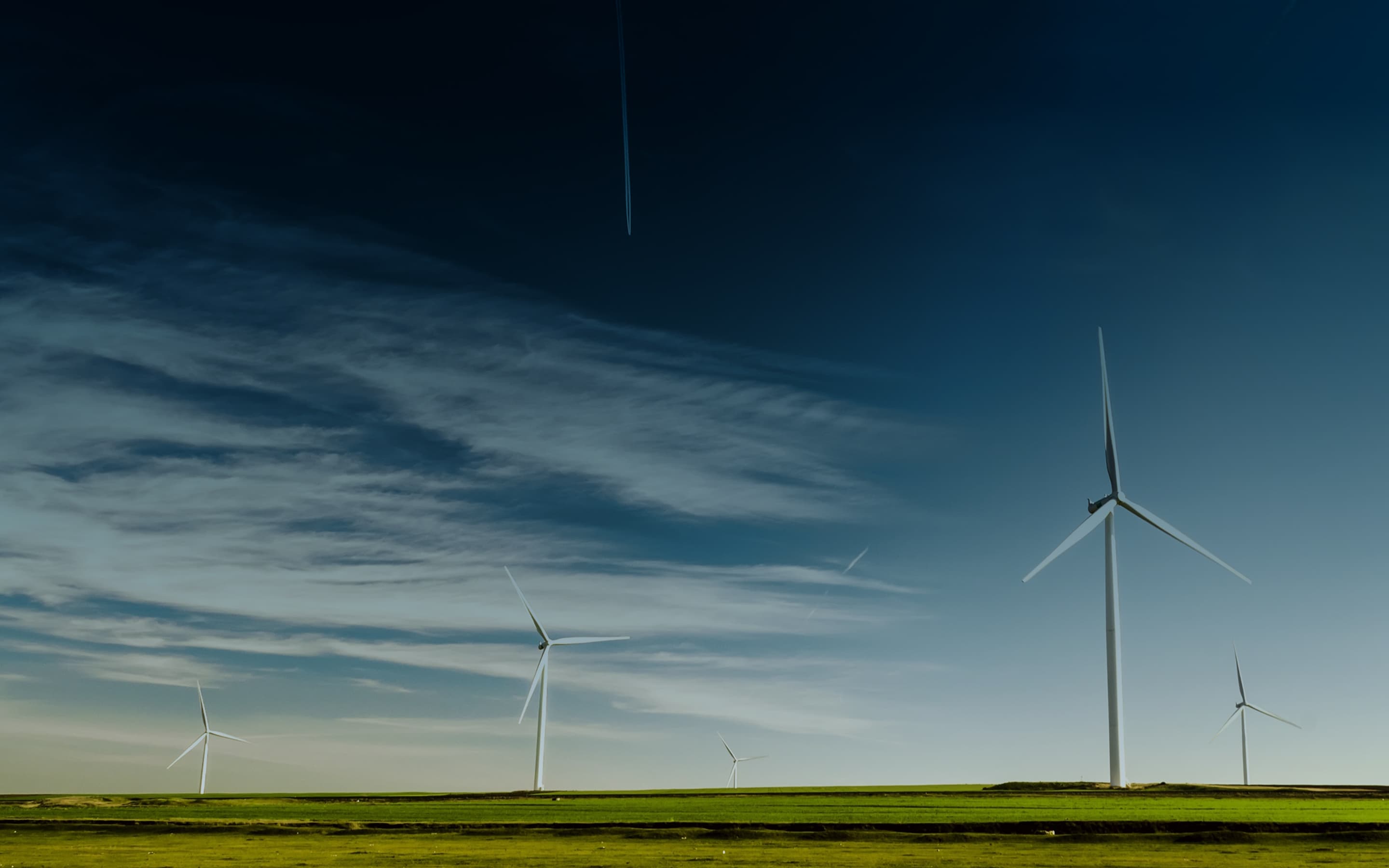 Eine weite Landschaft mit Windrädern vor einem tiefblauem Himmel