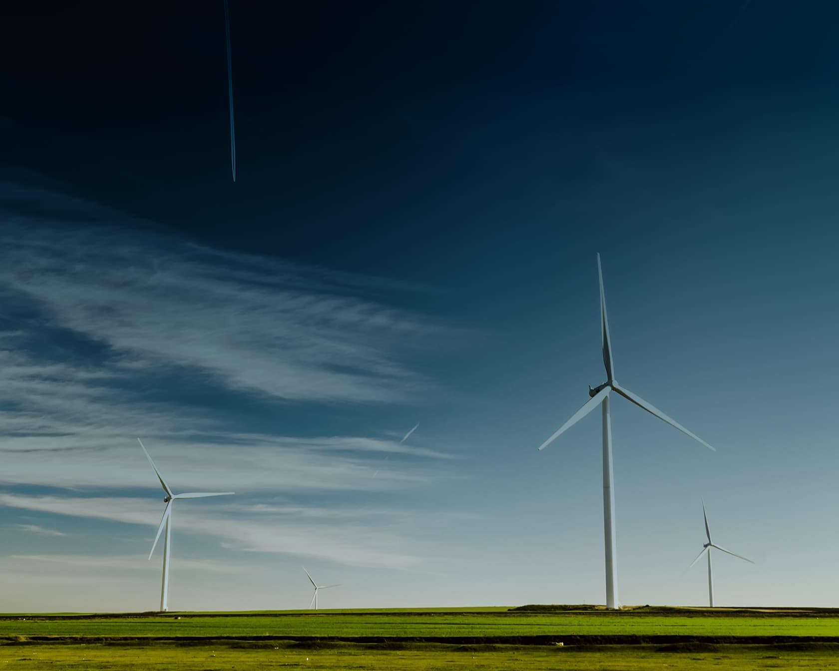 Eine weite Landschaft mit Windrädern vor einem tiefblauem Himmel