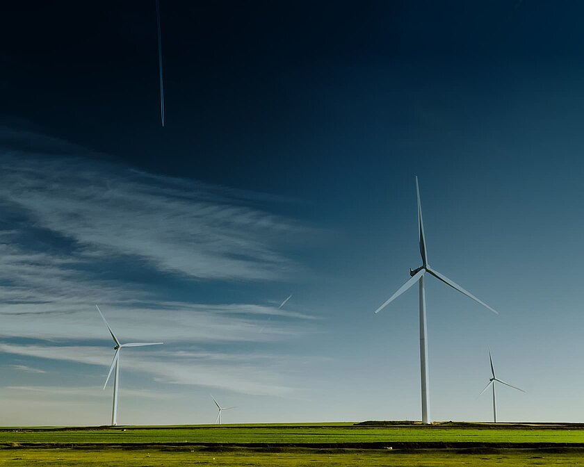 Eine weite Landschaft mit Windrädern vor einem tiefblauem Himmel